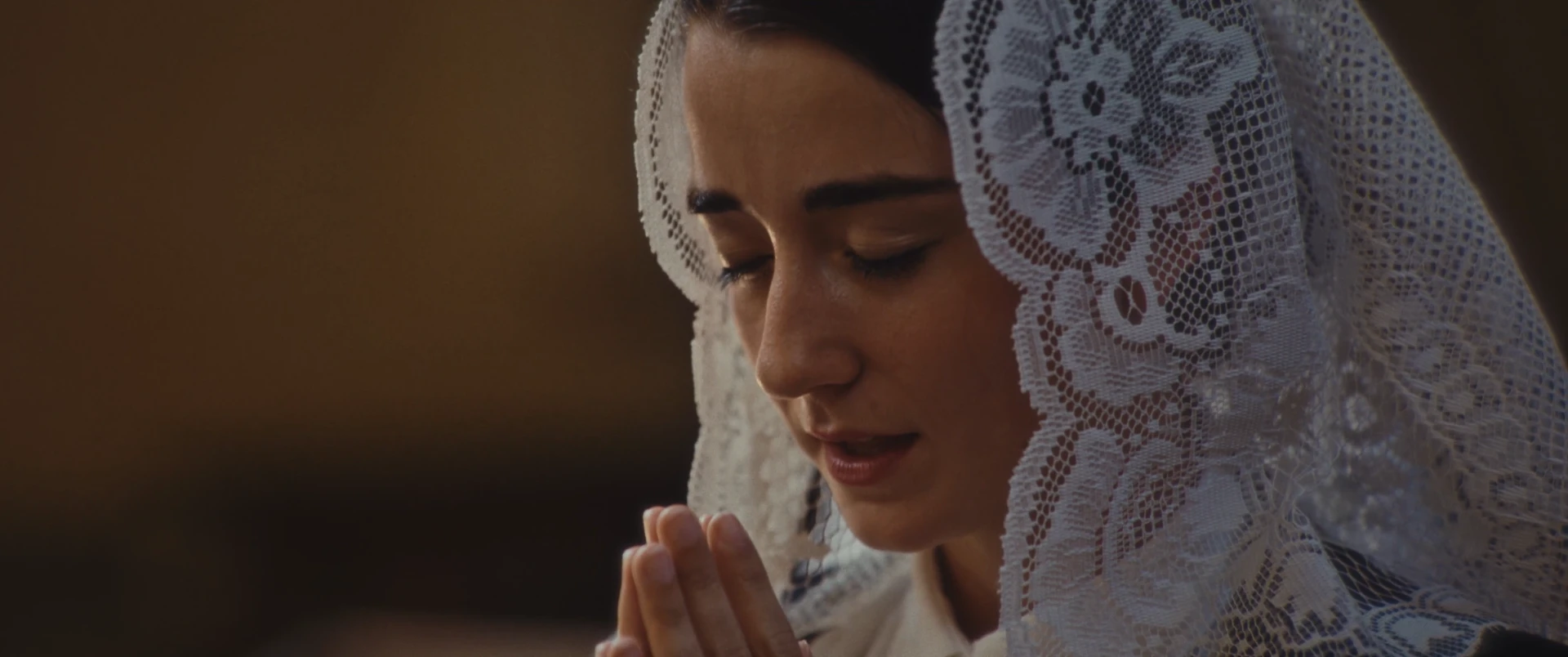 Eine Frau im weißen Spitzenschleier betet – eine Szene aus dem Film Pier Giorgio Frassati